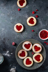 Cookies with raspberry jam, red hearts on a blue table.