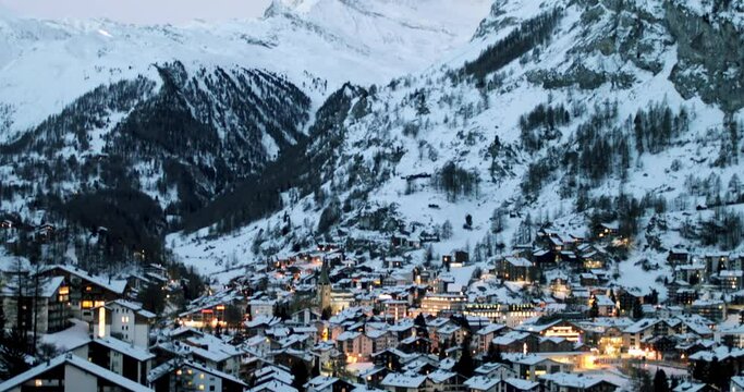 Cityscape of the Swiss village of Zermatt in Valais in winter, at dawn with snow and illuminations. The Matterhorn and the Alpine mountain range in the background.
