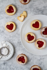 Linzer cookies with raspberry jam, red hearts on white plates.
