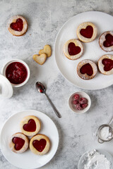 Cookies with red hearts with raspberry jam on white plates, top view.