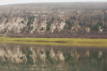 Scenic panoramic view of a river. Hills, pines and stones as a background. Reflection in the river.