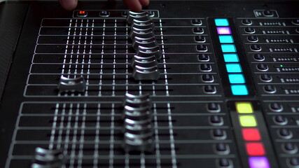 Man works on a professional electronic audio mixer. A control panel for tuning sound channels.