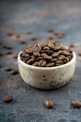 Сoffee beans in a ceramic bowl - selective focus. Scattered coffee beans on a background. High quality photo