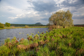 A small boggy pond against the backdrop of secluded mountains and a picturesque sky.