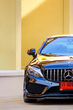 Samut Sakhon, Thailand - January 08,2021: Colorful natural light reflection on half of black car Mercedes-Benz C43 AMG parked on street in vertical frame, illustrative editorial
