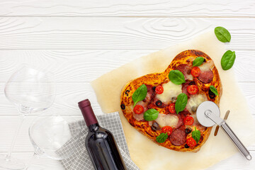 .Valentine's day table setting. Heart pizza with wine, glasses and gift box