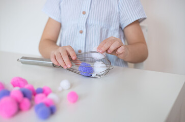 Toddler fine motor and learning activity with household items. DIY, child pulling out whisk with pom pom.