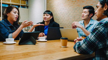 Group of happy young Asia business coworkers using laptop in team casual meeting, startup project discussion at cafe restaurant. Coffee shop holiday activity, modern friendship lifestyle concept.