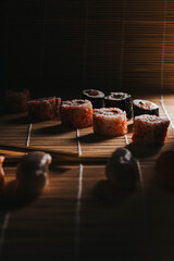 Sushi. Comida japonesa sobre esterilla. Foto de nigiri y maki sushi con luz lateral. Composición de comida asiática.	