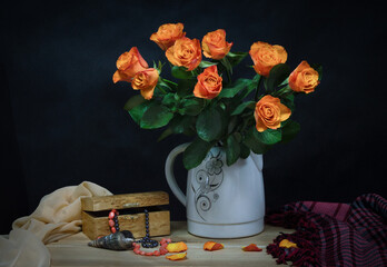Still life with a bouquet of beautiful pale orange roses, a Karelian birch box, a string of coral beads and a sea shell.