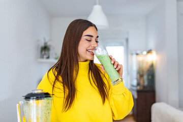 Woman drinking green detox smoothie drink. Happy smiling girl with glass of healthy fresh raw...