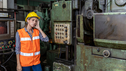 Female mechanical engineer or factory worker with hardhat and safety uniform operating a heavy...