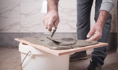 Worker putting adhesive to the tile.