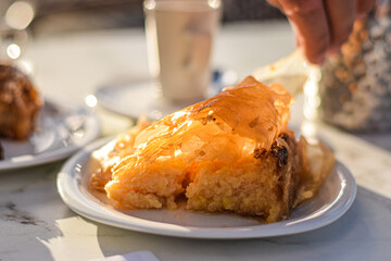 Big piece of traditional greek baklava cake served on two plates with coffee