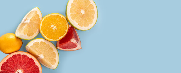 Flatlay pattern of citrus orange, lemon, lime and grapefruit slices on blue background. top view, banner