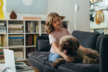 teenager girl sitting on sofa with her dog at home