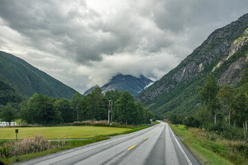 Road through a valley with clouds at the mountains