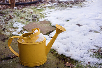 metal watering can covered with snow - obrazy, fototapety, plakaty