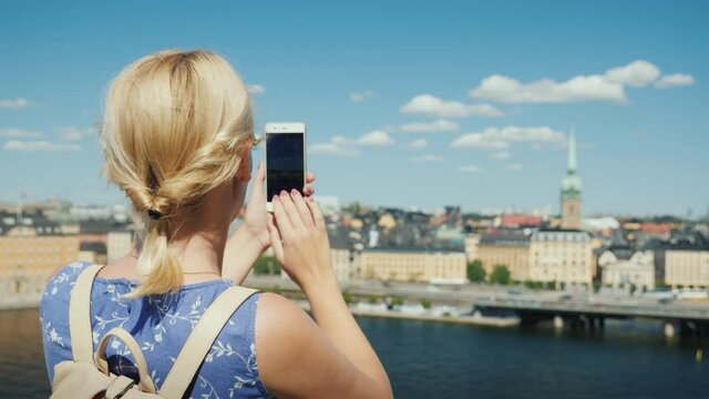 A woman is photographing a beautiful view of the city of Stockholm in Sweden, rear view. Tourism in Scandinavia concept