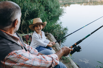 boy with his grandfather fishing together outdoor on the lake