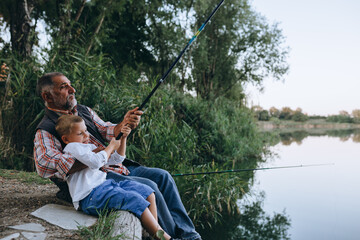 boy with his grandfather fishing together outdoor on the lake