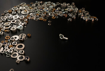 bolts, screws, nuts on a black background scattered. concept of individualism