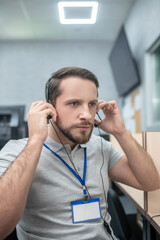 Serious man putting on headphones tuning headset