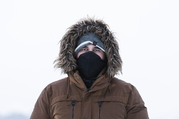 Person with coat in the snow and mask
