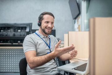 Smiling gesturing man in headphones near laptop