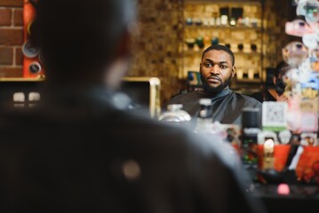 Black man in the barbershop. Cute black man makes a haircut in the African salon. Hair style. Haircut for adults.