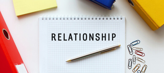 Notepad with text RELATIONSHIP on a white background, near document folder and office supplies.