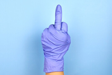 A woman's hand in a medical glove shows a middle finger gesture.