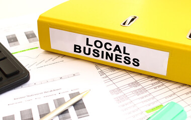 A yellow folder with documents labeled LOCAL BUSINESS lies on the office desk.