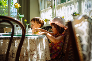 Children are sitting at a cafe table. Girl with a boy talking. Meeting at the cafe. Image with selective focus.