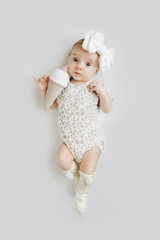 Cute baby with knitted ice cream. Adorable stylish baby in stylish clothes and headband looking at camera while lying on gray background. Fashion baby.