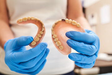 Old dental prosthesis in medical hands before prosthetics work.