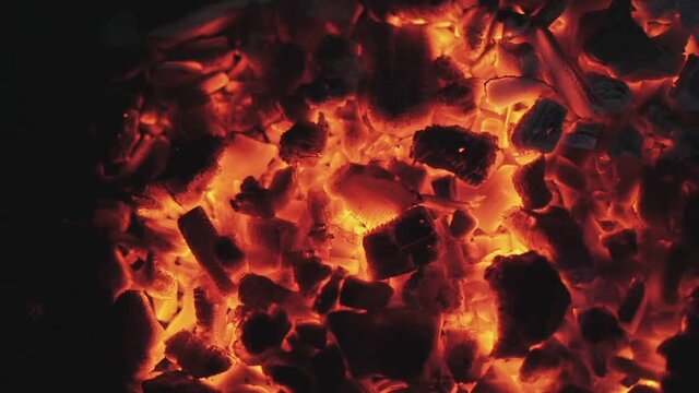 Coals smolder beautifully in the fire. Close-up.