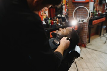 Naklejka na ściany i meble Visiting barbershop. African American man in a stylish barber shop