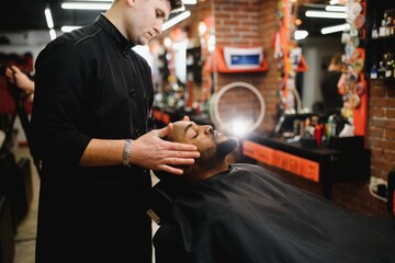 African male client getting haircut at barber shop from professional hairstylist.