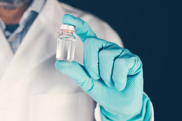 Laboratory technician holding vaccine vial bottle in hand