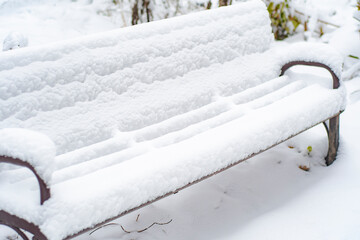 An empty, snow-covered bench in a winter park.