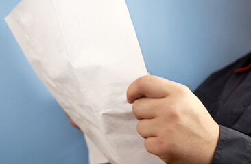 A man in his hands holds a document or drawing on a blue background.