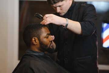 Black man in the barbershop. Cute black man makes a haircut in the African salon. Hair style....