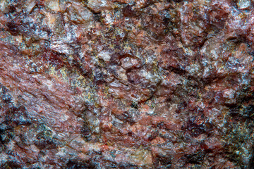 Background with the surface of a piece of red granite interspersed with quartz in soft focus under high magnification