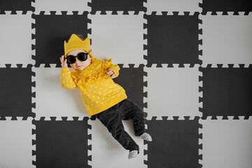 Stylish baby lying on jigsaw floor - obrazy, fototapety, plakaty
