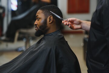 Black man in the barbershop. Cute black man makes a haircut in the African salon. Hair style. Haircut for adults.