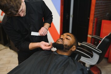 Fototapeta premium Visiting barbershop. African American man in a stylish barber shop
