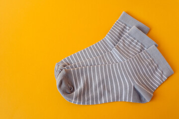 Gray socks with white stripes on a yellow background, top view, space for text