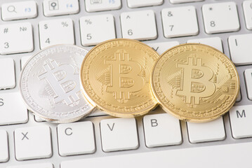 Closeup photo of golden and silver bitcoin lying on white keyboard buttons