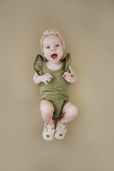 Baby in stylish clothes smiling and laughing on brown background. Fashion baby. Happy childhood.